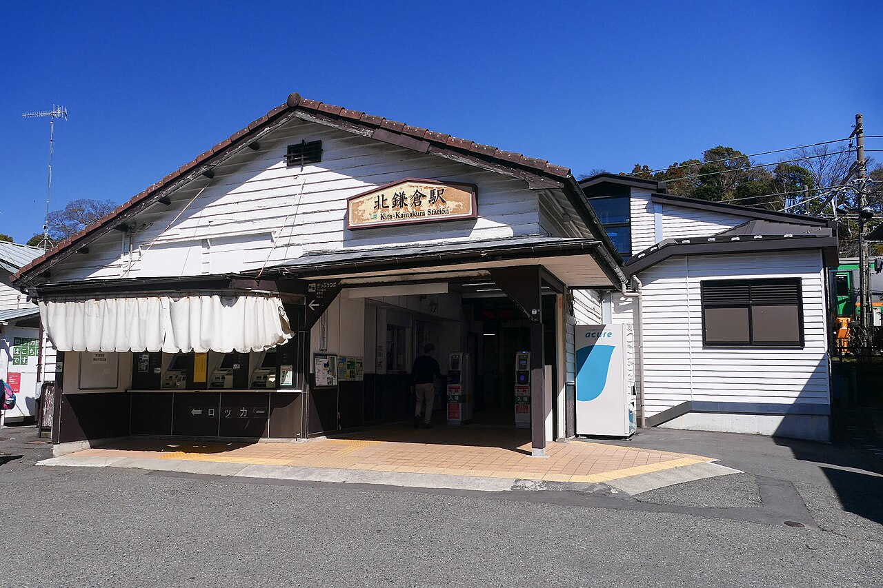 The wooden west entrance of Kita-Kamakura Station under a clear blue sky